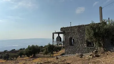 a stone building on top of a hill with trees at Olive house in Um Qeis
