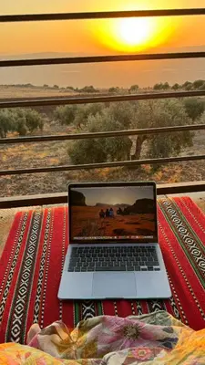 a laptop computer sitting on a table in front of a train at Olive house in Um Qeis