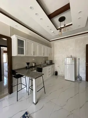 a large kitchen with a table and a refrigerator at Sawa Apartment in Amman