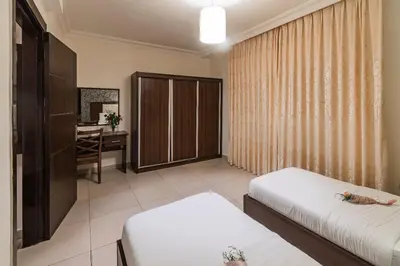 a hotel room with two beds and a desk at Lancaster Hotel Apartments-Gardens in Amman