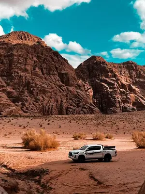 a white truck parked in the desert near mountains at RUM CITY STAR BUBBLE lUXURY CAMP in Wadi Rum