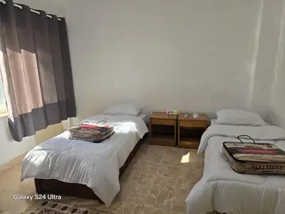 a room with three beds and a table and a window at Lukanda Apartment Feel at Home in Amman