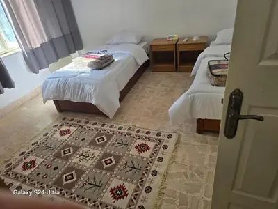 a bedroom with two beds and a rug on the floor at Lukanda Apartment Feel at Home in Amman