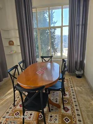 a dining room table and chairs in front of a window at Lukanda Apartment Feel at Home in Amman
