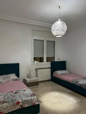 a bedroom with two beds and a chandelier at carfort House in Al Jafr