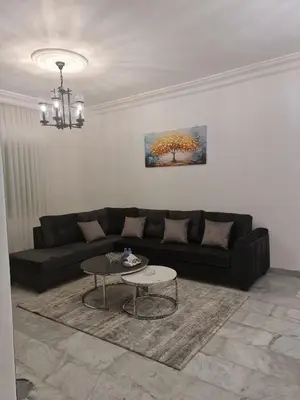a living room with a black couch and a table at Layal's apartment in Amman