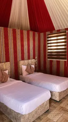 two beds in a room with red and gold walls at Amin Camp in Wadi Rum