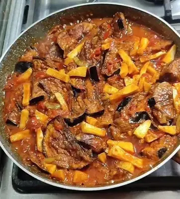 a pan filled with meat and vegetables on a stove at jarmy house in Ash Shajarah