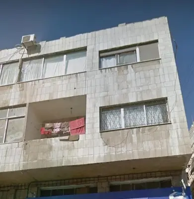 a tall building with windows and laundry hanging from it at الدونق in Amman