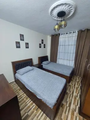 a bedroom with two beds and a chandelier at New zarqa20 km from Amman in Az Zarqa