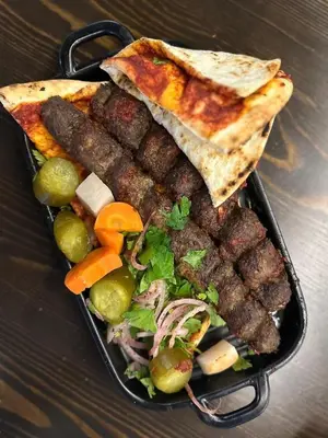 a tray of food with bread and a salad and food at Cool apartment in Maḩaţţat al Jufūr
