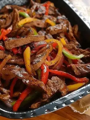 a stir fry with beef and vegetables in a pan at Cool apartment in Maḩaţţat al Jufūr