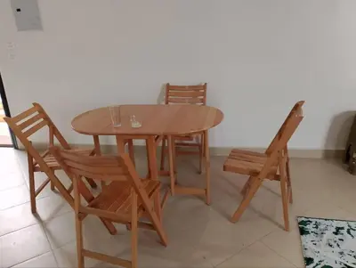 a wooden table and two chairs and a table and a chair at Cool apartment in Maḩaţţat al Jufūr