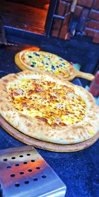 three pizzas sitting on top of a table at Cool apartment in Maḩaţţat al Jufūr