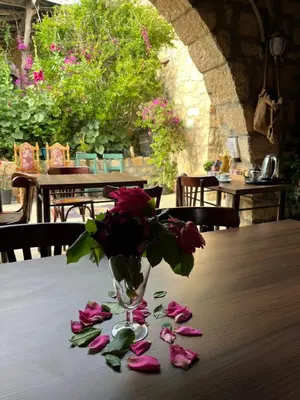 a vase with flowers on a table with pink shoes at Hartna zaman in Taiyiba