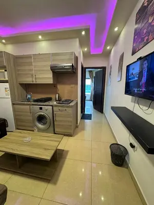 a kitchen with a stove and a tv on the wall at Al Tamimi Furnished Apartments in Amman