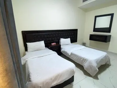 two beds in a hotel room with a mirror at سهول الكرمل للأجنحة والشقق الفندقية in Amman