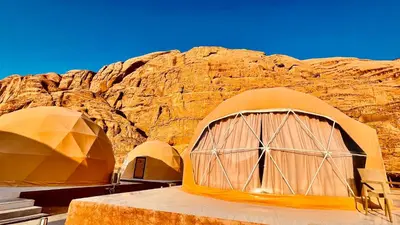 a group of tents in front of a rocky mountain at Aethera Sky Retreat Wadi Rum in Wadi Rum