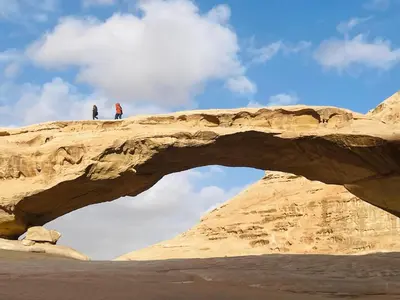 two people standing on top of a rock bridge at Aethera Sky Retreat Wadi Rum in Wadi Rum