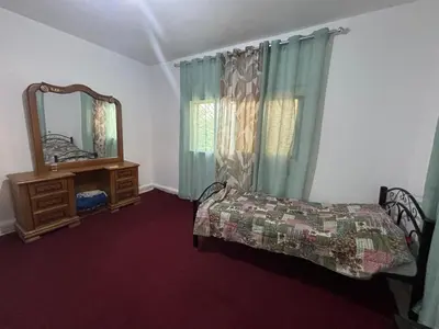 a bedroom with a bed and a mirror and a dresser at Leith Holiday Home in ‘Ayn Jannā