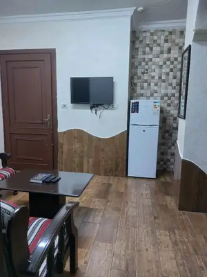 a living room with a refrigerator and a table and a tv at رياحين الخلود للشقق الفندقية in Amman