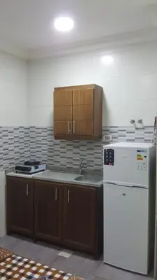 a kitchen with a white refrigerator and wooden cabinets at رياحين الخلود للشقق الفندقية in Amman