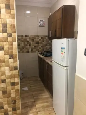 a kitchen with a white refrigerator and wooden cabinets at رياحين الخلود للشقق الفندقية in Amman