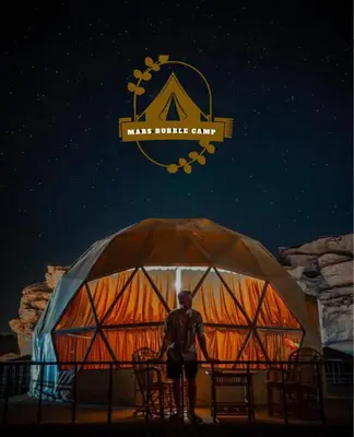 a man standing in front of a large tent at RUM MARS BUBBLE lUXURY CAMP in Wadi Rum