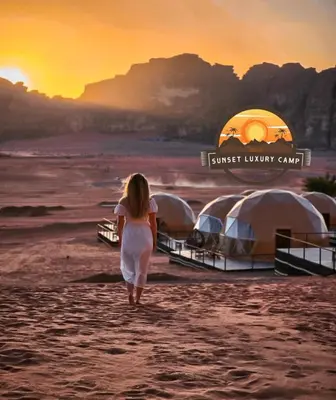 a woman walking down a beach with tents at RUM SUNSET BUBBLES lUXURY CAMP in Wadi Rum
