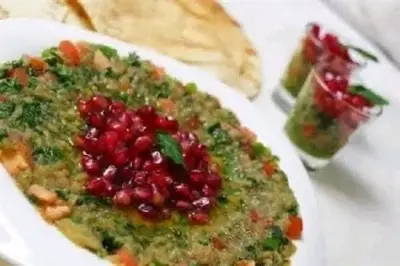a bowl of food with pomegranates on a plate at الخريطه هاوس in Tall al Misţāḩ