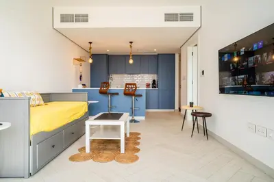 a bedroom with a yellow bed and a kitchen at Ayla B12 Beach Apartment Aqaba in Aqaba
