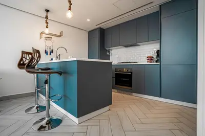 a kitchen with blue cabinets and a sink and a stool at Ayla B12 Beach Apartment Aqaba in Aqaba
