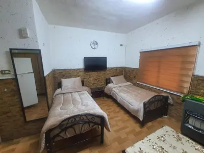 a bedroom with two beds and a flat screen tv at بيت الحجر in Amman