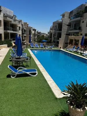a swimming pool with lounge chairs and blue umbrellas at Luxury home Abdoun complex in Amman
