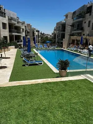 a large swimming pool with lawn chairs and blue umbrellas at Luxury home Abdoun complex in Amman