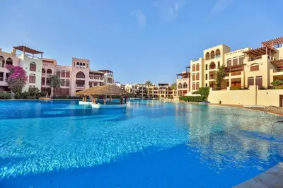 a large pool with blue water in front of buildings at Talabay two bedroom umniah pool in Aqaba