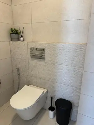 a bathroom with a toilet and a trash can at DAMAC Pool View Penthouse in Amman