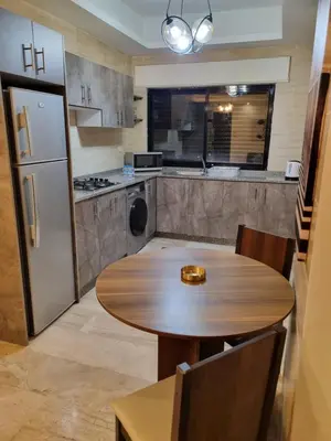 a kitchen with a wooden table and a refrigerator at unique 2bedroom at abdoun 001 in Amman