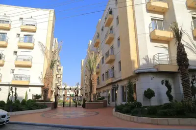 a large building with palm trees in front of it at Montana Residence in Amman