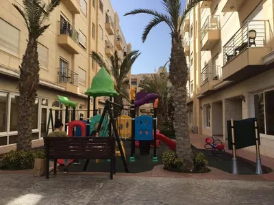 a playground in front of a building with palm trees at Montana Residence in Amman