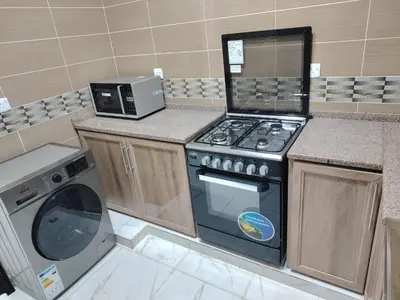 a kitchen with a stove and a washing machine at Al Wesam Furnished Apartments in Aqaba