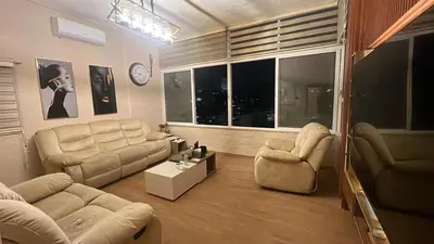 a living room with couches and chairs and a clock at Art loft in Amman