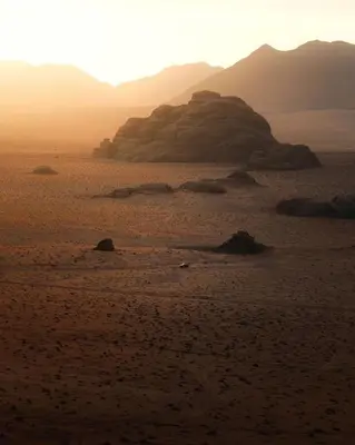 a sunset in the desert with mountains in the background at Wadi Rum Thamer in Wadi Rum