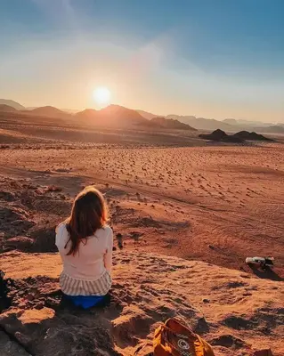 a little girl sitting in the desert watching the sunset at Wadi Rum Thamer in Wadi Rum