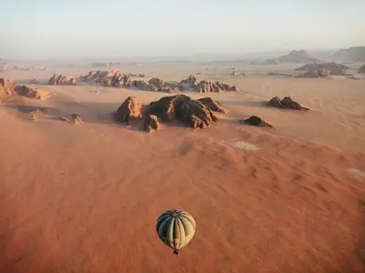 a hot air balloon flying over the desert at Wadi Rum Thamer in Wadi Rum