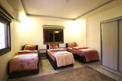 a room with three beds and a mirror at Mountain Echo Inn in Taiyiba