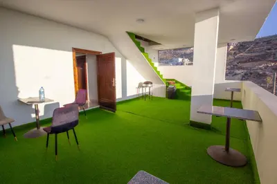 a room with green carpet and chairs and a table at Mountain Echo Inn in Taiyiba