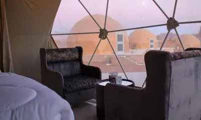 a room with two chairs and a bed and a window at Rum Pillars Camp in Disah
