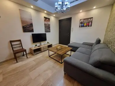 a living room with a gray couch and a television at unique 2bedroom at abdoun 006 in Amman