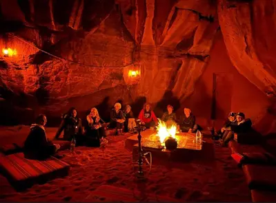 a group of people sitting around a fire in a cave at Wadi Rum sleeping in the desert in Wadi Rum